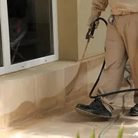General pest control technician spraying exterior perimeter around a home in Aurora, CO