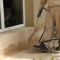 General pest control technician spraying exterior perimeter around a home in Aurora, CO