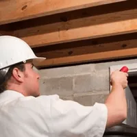 Termite inspection technician checking a basement wall and framing for termite activity in Aurora, CO