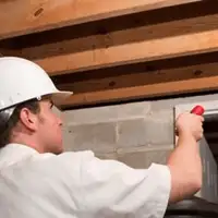 Termite inspection technician checking a basement wall and framing for termite activity in Aurora, CO
